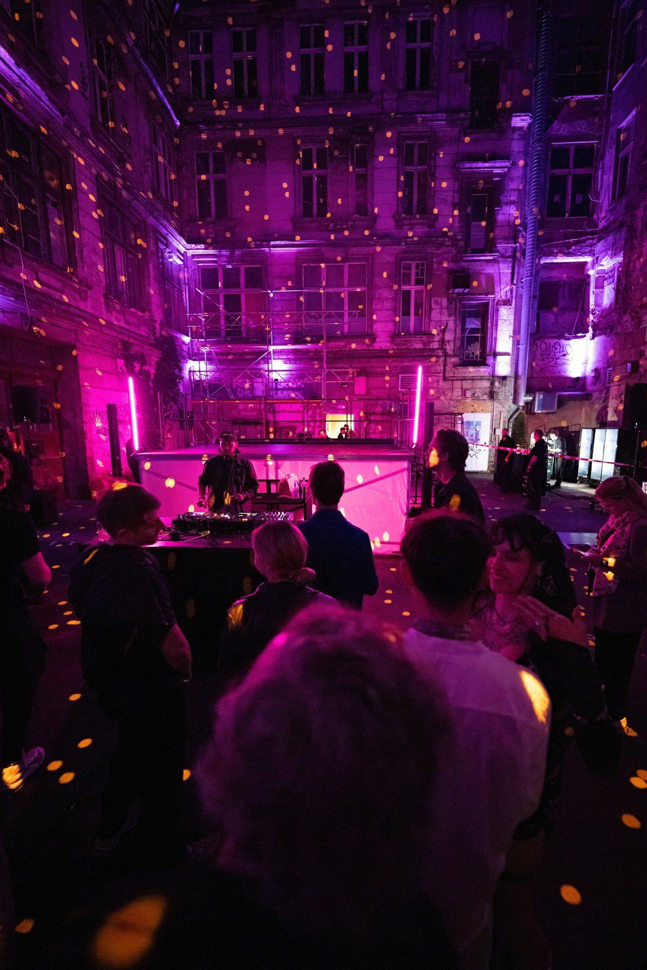 Die volle Hof-Verwandlung: gemappte Fassade in goldenen Lichtpunkten, DJ-Bühne und Publikum bei Nacht
